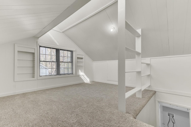 bonus room featuring lofted ceiling with beams, built in shelves, and carpet floors