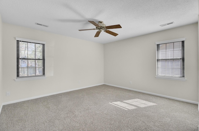 empty room with visible vents, baseboards, carpet floors, ceiling fan, and a textured ceiling