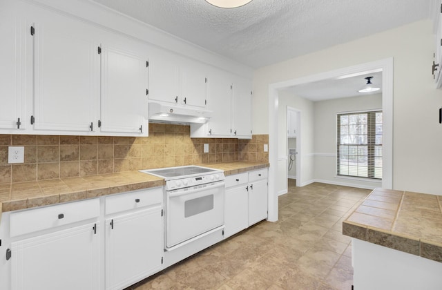 kitchen featuring white cabinets, tasteful backsplash, under cabinet range hood, and white range with electric cooktop