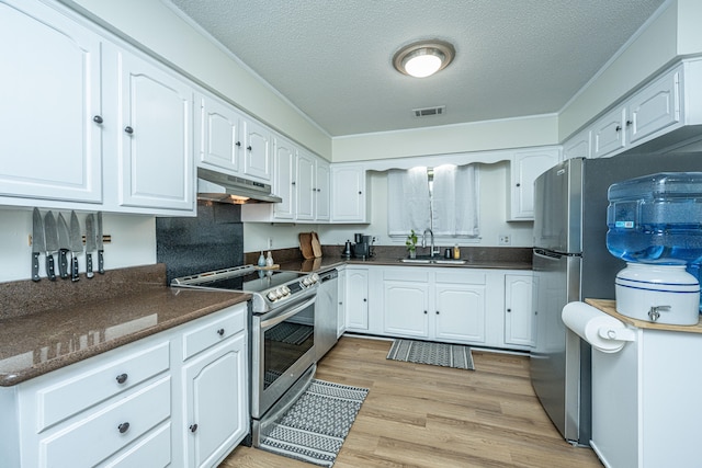 kitchen featuring appliances with stainless steel finishes, sink, white cabinets, and light hardwood / wood-style floors