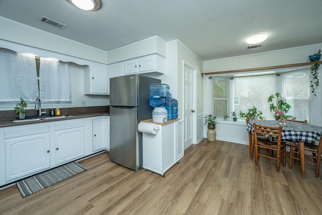 kitchen featuring stainless steel refrigerator, sink, white cabinetry, and light hardwood / wood-style floors