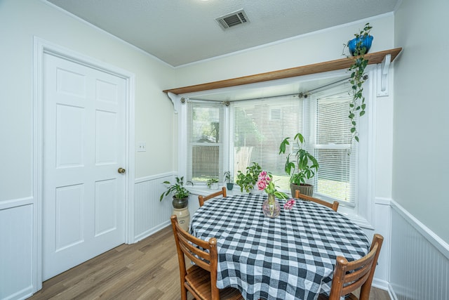 dining room featuring a textured ceiling, crown molding, and hardwood / wood-style floors