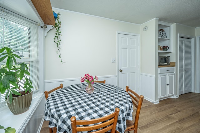 dining room featuring crown molding, a textured ceiling, and wood-type flooring