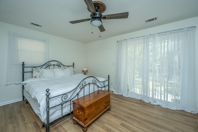 bedroom with a textured ceiling, ceiling fan, and light hardwood / wood-style floors