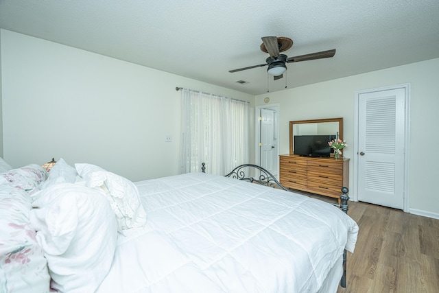 bedroom with a closet, a textured ceiling, ceiling fan, and light hardwood / wood-style floors