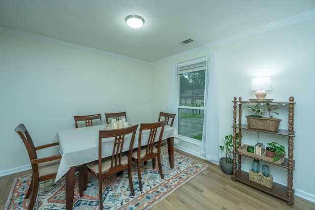 dining area with a textured ceiling, light hardwood / wood-style flooring, and ornamental molding