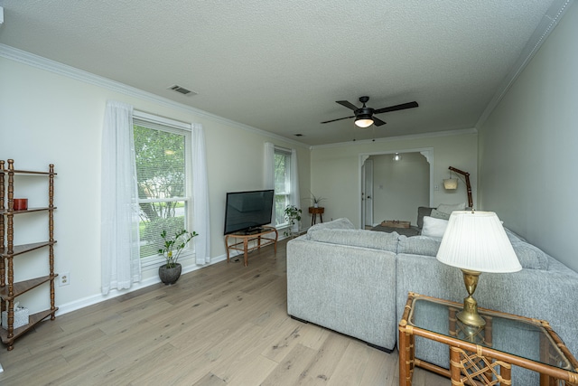 living room featuring a textured ceiling, crown molding, ceiling fan, and light wood-type flooring