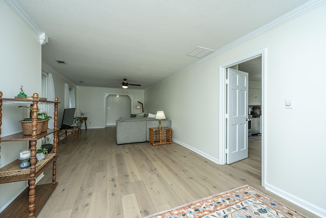 living room with crown molding, a textured ceiling, ceiling fan, and light hardwood / wood-style floors