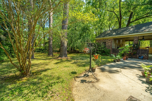 view of yard with ceiling fan and a patio