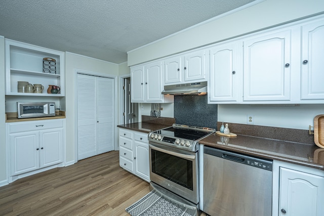 kitchen featuring a textured ceiling, stainless steel appliances, white cabinetry, and light hardwood / wood-style floors