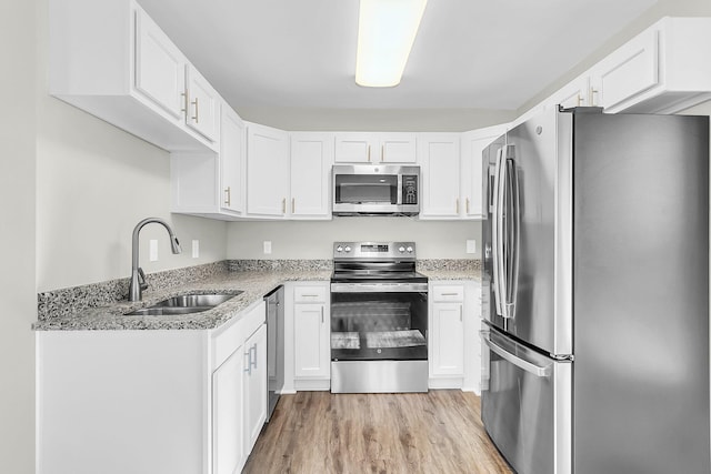 2711 Henry St, North Charleston, SC 29405 - kitchen featuring stainless steel appliances, a sink, light stone countertops, light wood-type flooring, and white cabinetry