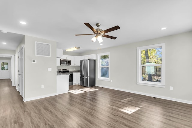 kitchen featuring a wealth of natural light, white cabinets, dark wood-type flooring, and appliances with stainless steel finishes