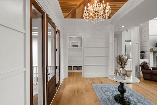 foyer entrance with decorative columns, light hardwood / wood-style flooring, wood ceiling, ornamental molding, and a chandelier