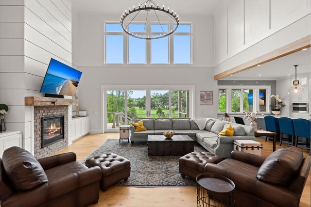 living room with an inviting chandelier, light hardwood / wood-style floors, and a high ceiling