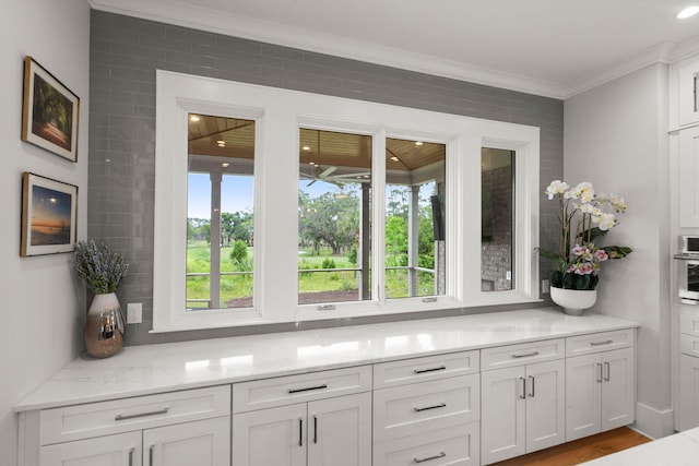 interior details with hardwood / wood-style flooring, tasteful backsplash, and ornamental molding