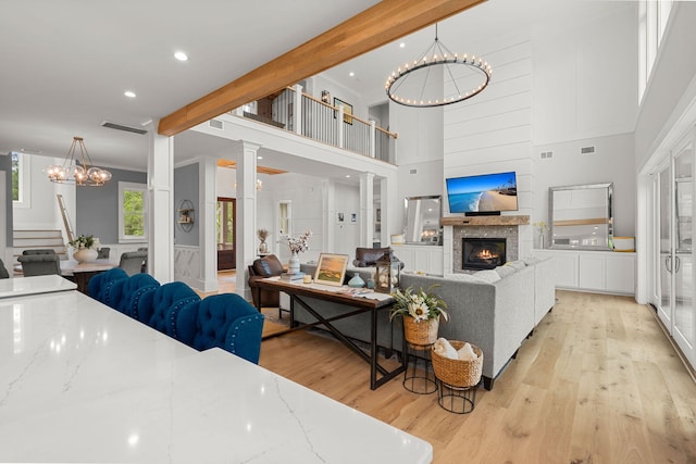 living room with beamed ceiling, light hardwood / wood-style floors, and a notable chandelier