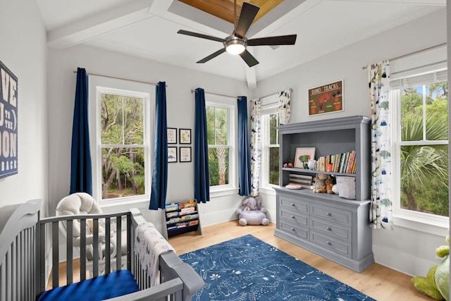 bedroom with light hardwood / wood-style floors, a nursery area, and ceiling fan