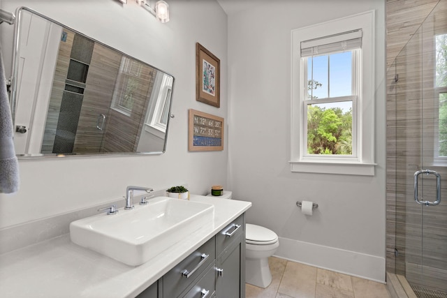 bathroom with a shower with shower door, vanity, toilet, and a healthy amount of sunlight