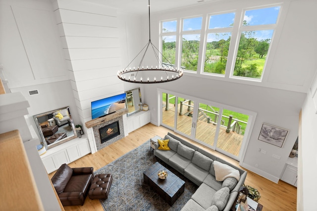 living room featuring light hardwood / wood-style flooring, a high ceiling, and an inviting chandelier