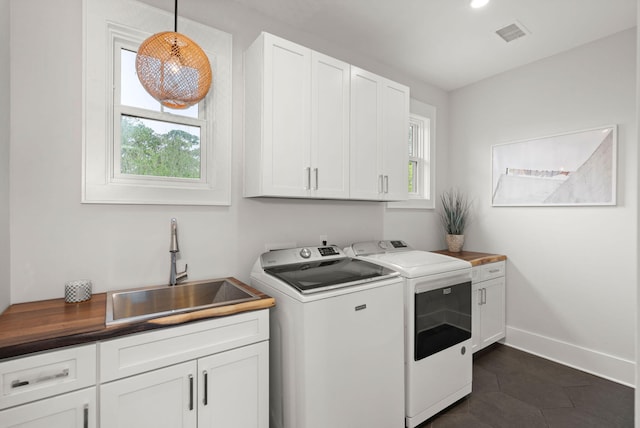 laundry area featuring sink, cabinets, and washer and clothes dryer