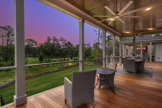 deck at dusk with ceiling fan and a lawn