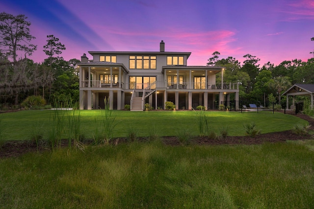 back house at dusk featuring a yard and a sunroom