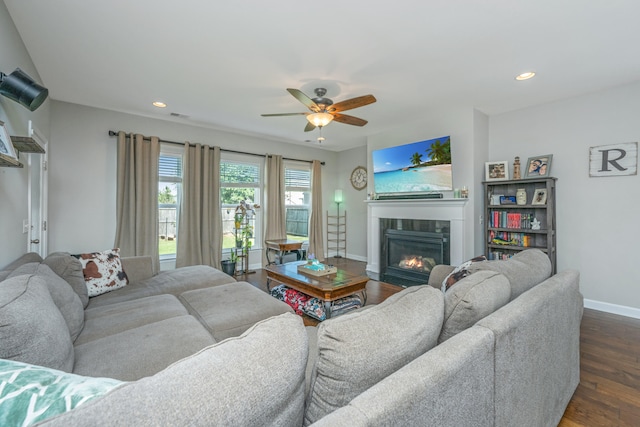 living room with a tile fireplace, dark hardwood / wood-style floors, and ceiling fan