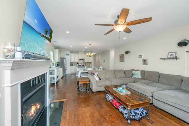 living room with ceiling fan with notable chandelier and dark wood-type flooring