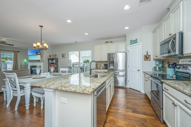 kitchen with white cabinets, sink, a kitchen island with sink, dark wood-type flooring, and appliances with stainless steel finishes