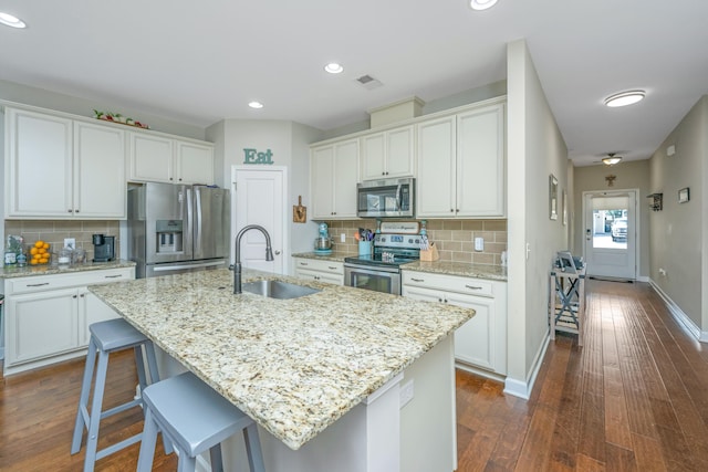 kitchen featuring white cabinets, an island with sink, sink, stainless steel appliances, and dark hardwood / wood-style floors