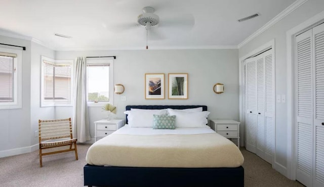 carpeted bedroom with ceiling fan, ornamental molding, and multiple closets