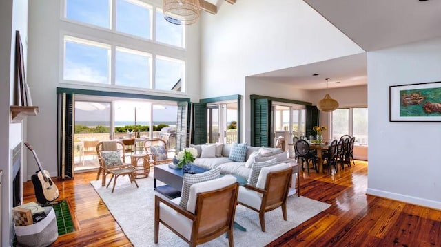 living room with a wealth of natural light, hardwood / wood-style floors, and a towering ceiling