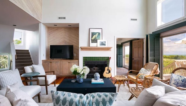 living room with hardwood / wood-style flooring, a high ceiling, a tile fireplace, and a healthy amount of sunlight