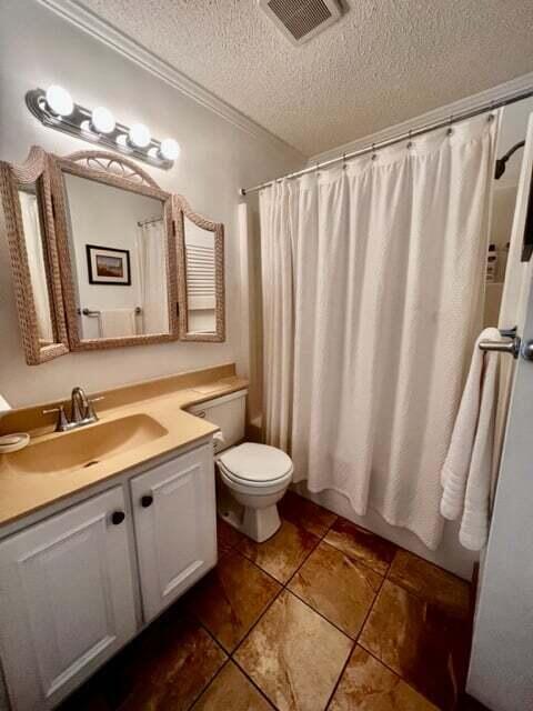 bathroom with a textured ceiling, visible vents, tile patterned flooring, vanity, and toilet