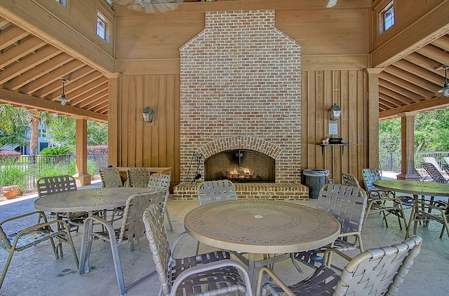 view of patio with an outdoor brick fireplace, outdoor dining space, and fence