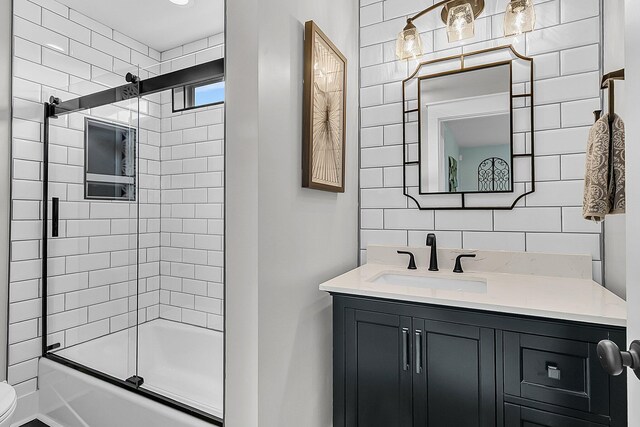 bathroom with vanity, bath / shower combo with glass door, tasteful backsplash, and toilet