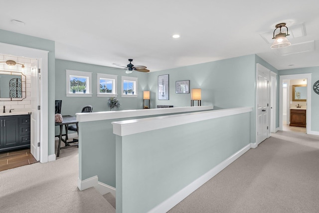 bar area featuring light colored carpet, baseboards, ceiling fan, and a sink