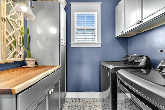 laundry area featuring washing machine and clothes dryer, cabinet space, and baseboards