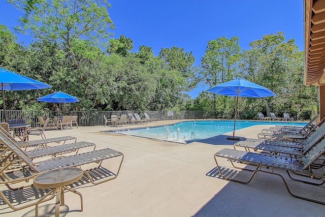 community pool featuring fence, a patio, and view of scattered trees