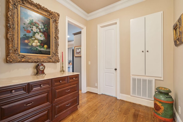 hall featuring light wood-style floors, baseboards, visible vents, and ornamental molding