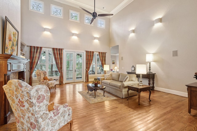 living area featuring light wood finished floors, baseboards, ceiling fan, ornamental molding, and a fireplace