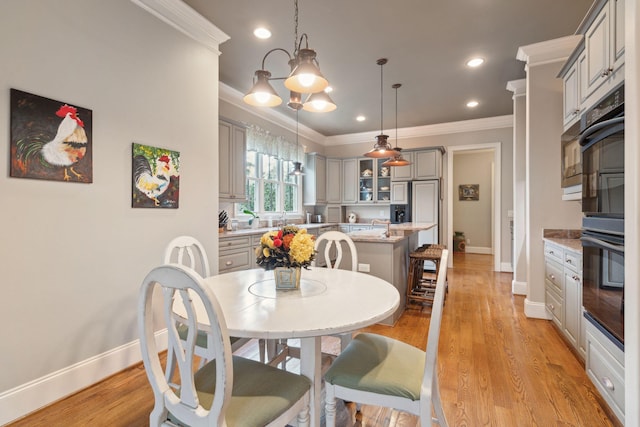 dining area with light wood finished floors, baseboards, and ornamental molding