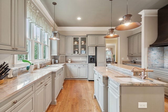 kitchen featuring pendant lighting, gray cabinets, a sink, and light stone counters