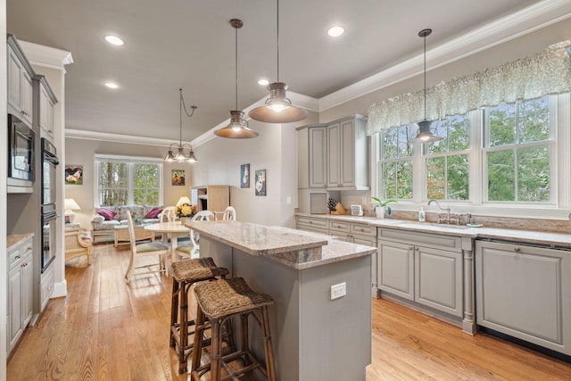 kitchen with open floor plan, decorative light fixtures, a center island, gray cabinetry, and a sink