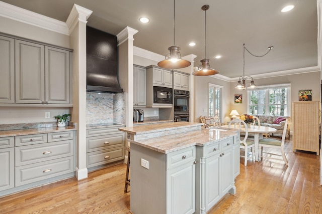 kitchen featuring a kitchen island with sink, hanging light fixtures, custom exhaust hood, gray cabinets, and black appliances