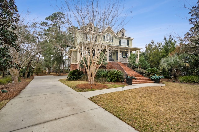 view of front of property with covered porch, driveway, stairway, and a front lawn