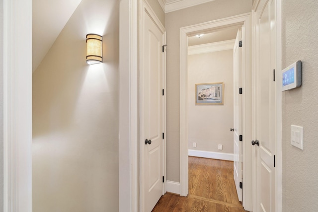 corridor featuring crown molding, wood finished floors, and baseboards