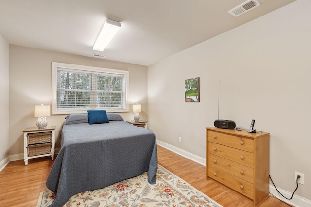 bedroom with light wood-type flooring, visible vents, and baseboards