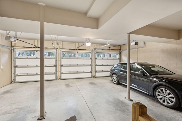 garage featuring a garage door opener and concrete block wall