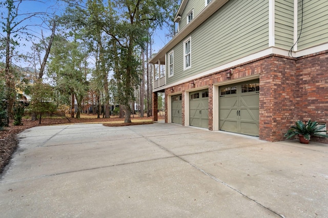 view of side of property featuring concrete driveway, brick siding, and an attached garage